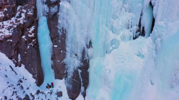 Mountaineer Man está liderando en Ice. Escalada de hielo en cascada congelada. Vista aérea — Vídeos de Stock