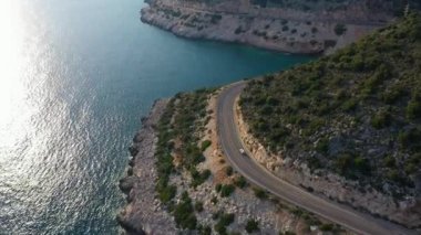 Car on Road along Coastline. Sea and Hills. Aerial View. Turkey. Drone Flies Forward