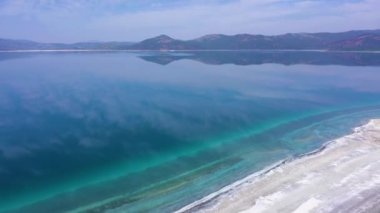 Lake Salda on Sunny Day. Crater Lake. Burdur Province, Turkey. Aerial View. Clouds Reflection. Drone Flies Forward, Tilt Up. Reveal Shot