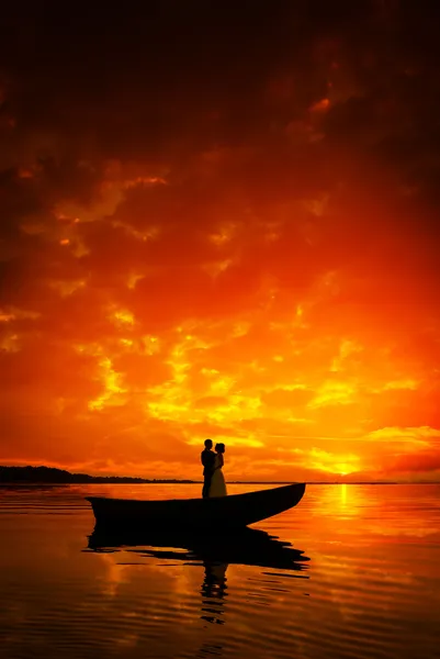 Σιλουέτα του ένα ζευγάρι φιλιούνται στο σκάφος στον ποταμό στο ηλιοβασίλεμα — Φωτογραφία Αρχείου