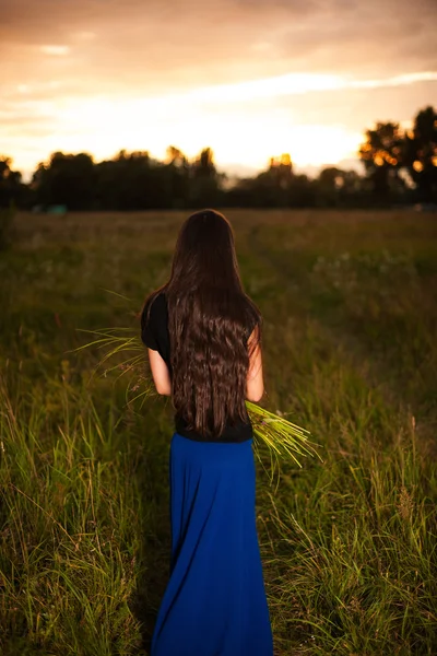 Beautiful woman with long natural hair holding bouquet of wild flowers — Stock Photo, Image