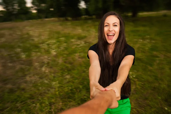 Молодая счастливая женщина кружится, держа мужчину за руку. — стоковое фото