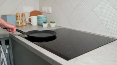 Kadın eli mutfaktaki modern indüksiyon sobasını açıyor.