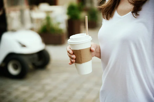 Femme tient tasse de café en papier à la rue de la ville — Photo