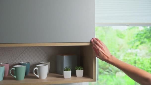 Kvinna öppet kök skåp dörr och sätta skålen inuti — Stockvideo