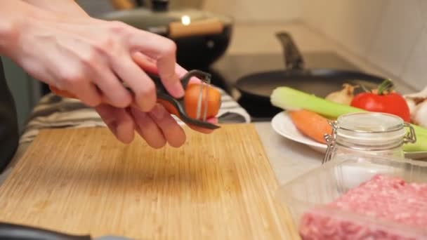 Woman scratchs carrot in kitchen, close up — Stock Video