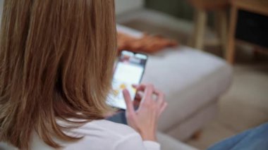 Oturma odasında akıllı telefon kullanan bir kadın.