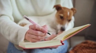 Kadın evde deftere notlar yazıyor.