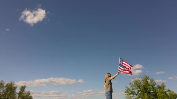 Mujer sostiene ondeando bandera americana — Vídeo de stock