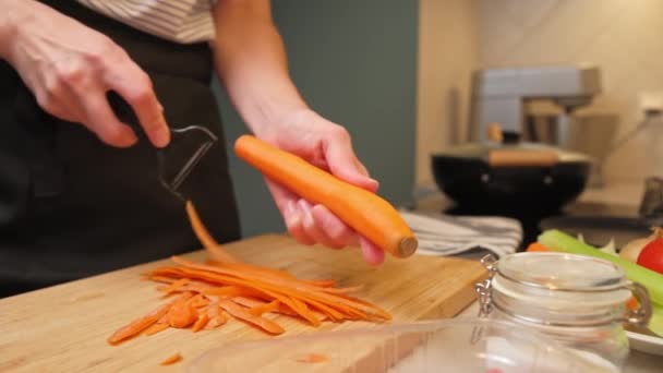 Femme gratte la carotte dans la cuisine, gros plan — Video