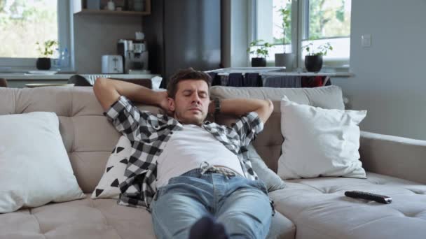 Мужчина лежит на диване и смотрит телевизор — стоковое видео