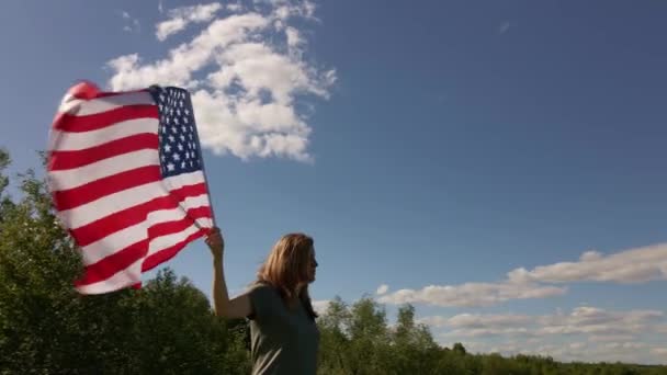 Mujer sostiene ondeando bandera americana — Vídeo de stock