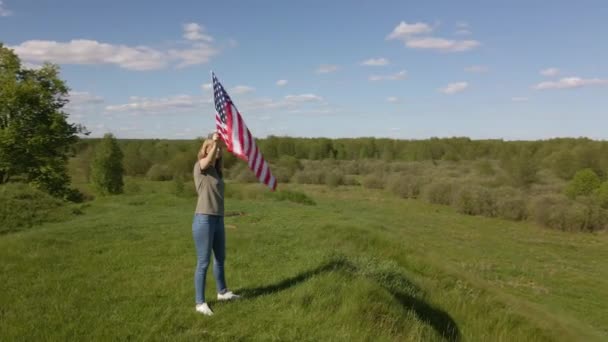 Mujer sostiene ondeando bandera americana — Vídeo de stock