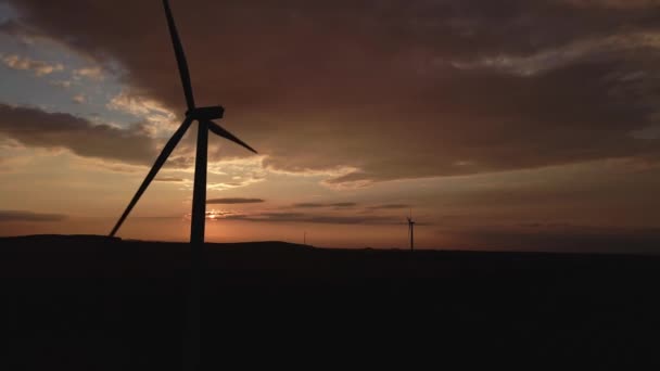 Silhouet van windmolen turbine in het veld bij zonsondergang hemel. Roterende windgenerator — Stockvideo