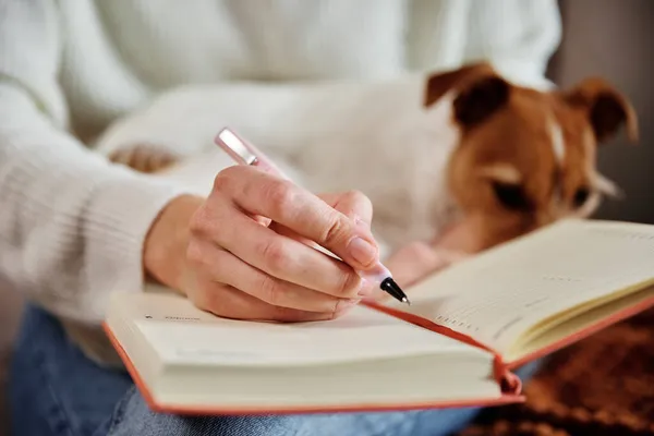 Frau schreibt Notizen in Notizbuch zu Hause — Stockfoto