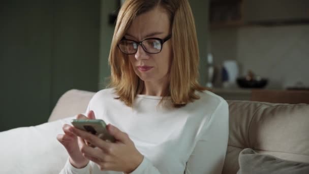 Kvinna som använder smartphone i vardagsrummet — Stockvideo