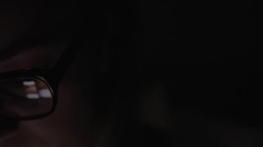 Gözlüklü kadın gece akıllı telefon kullanıyor.