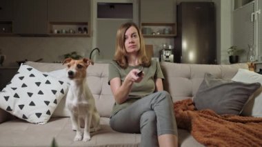 Köpekli bir kadın, otobüste televizyon izliyor.
