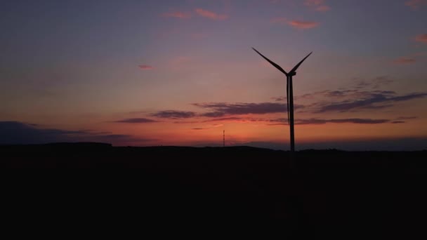 Sylwetka turbiny wiatrowej na polu o zachodzie słońca. Obrotowy generator wiatru — Wideo stockowe