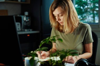 Kadın ev ofisinde uzaktan bilgisayar kullanarak çalışıyor.