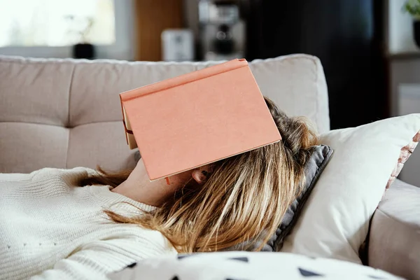 Mujer duerme en sofá con libro —  Fotos de Stock
