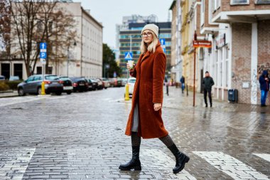 Şehir caddesinde elinde kahve fincanı olan kadın.