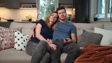 Cuple kanepede televizyon izliyor.