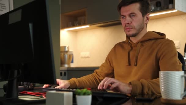 El hombre trabaja en la oficina en casa de forma remota, utilizando la computadora — Vídeo de stock