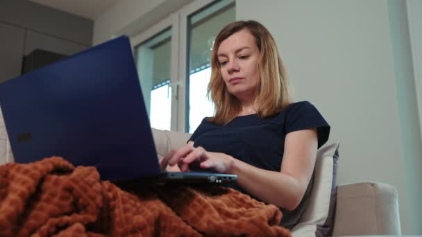 Mujer acostada en el sofá y el uso de ordenador portátil — Vídeos de Stock