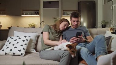 Oturma odasında akıllı telefon kullanan çift.