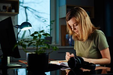 Kadın ev ofisinde uzaktan bilgisayar kullanarak çalışıyor.