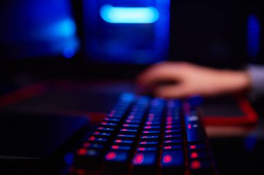 Genç çocuk karanlık odada bilgisayar oyunu oynuyor, neon renkli rgb mekanik klavye kullanın, siber spor oyunları için işyeri