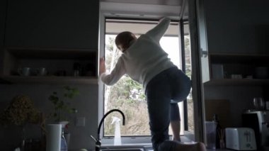 Evdeki kirli pencereleri temizleyen kadın, ev işleri rutini.