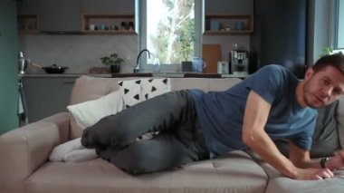 Kafkasyalı yorgun bir adam kanepede kıvranıyor, uzaktan kumandayı eline alıyor ve TV seyrediyor, tembel bir hafta sonu.