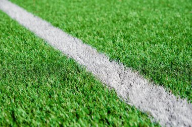 Futbol ya da futbol sahasının bir kısmı kapalı, beyaz sınır çizgileri olan sanatsal yeşil çimenler, kıvılcım oyunları için stadyumda Astroturf