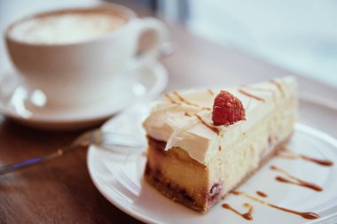 Bir fincan kahve ve bir parça ahudududulu kek pencerenin yanındaki sehpada, halka açık bir yerde kahvaltı.