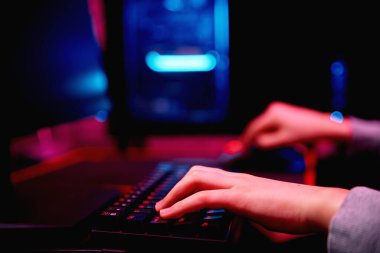 Genç çocuk karanlık odada bilgisayar oyunu oynuyor, neon renkli rgb mekanik klavye kullanın, siber spor oyunları için işyeri