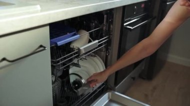 Kadın bulaşık makinesinden temiz yemek makinesini, zaman tasarrufu için mutfak aletini çıkardı.