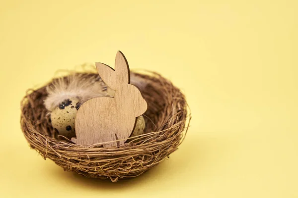 Mutlu Paskalya süslemeleri, sarı arka planda tahta tavşan ve yumurtalar. — Stok fotoğraf