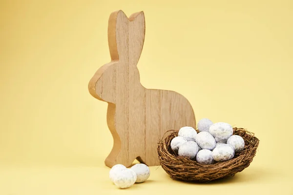 Buona Pasqua decorazione, Coniglio di legno e uova su sfondo giallo — Foto Stock