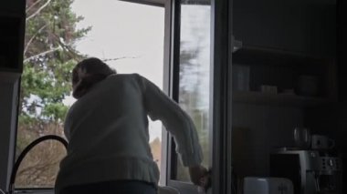 Evde pencereyi temizleyen kadın