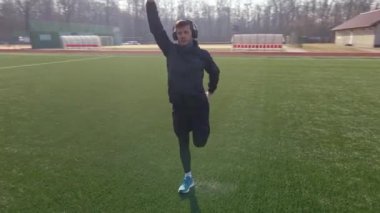 Sporcu adam koşmadan önce ısınma egzersizi yapar.