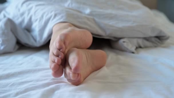 Ženské nohy v posteli pod přikrývkou — Stock video