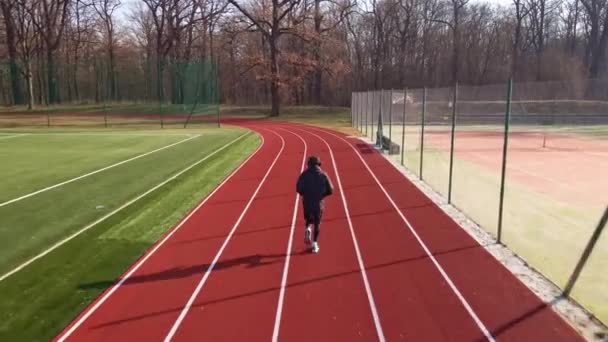 Hombre corriendo en pista de carreras en el estadio — Vídeo de stock