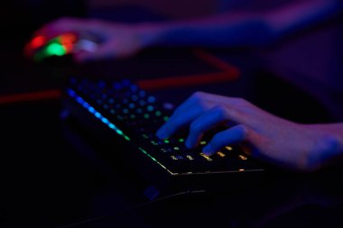 Profesyonel oyuncu karanlık odada bilgisayar oyunu oynar, neon renkli rgb mekanik klavye kullanın, siber spor oyunları için yer