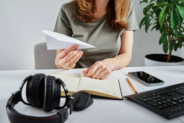 Woman plays with paper plane at workplace
