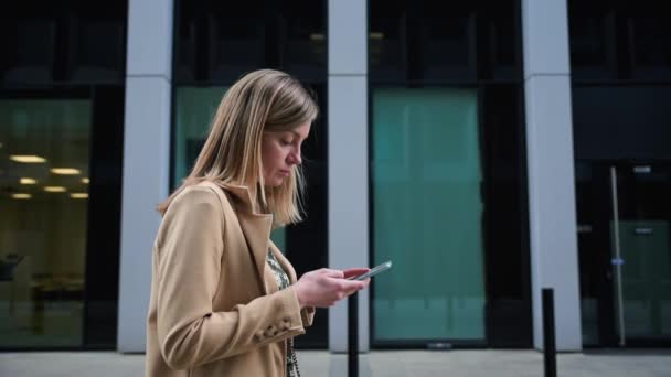 Nő sétál a város utcájában, és használja okostelefon — Stock videók