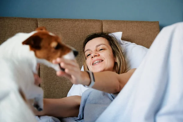 Mulher dormindo na cama e brincar com seu cão — Fotografia de Stock