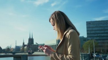 Nehir kenarındaki kadın akıllı telefon kullanıyor.