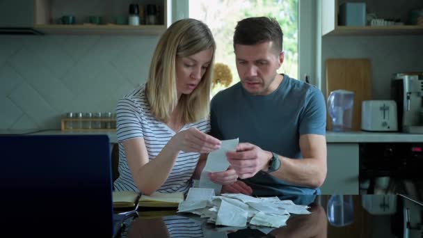 Άντρας και γυναίκα κοιτάζουν λογαριασμούς πληρωμών στην κουζίνα. — Αρχείο Βίντεο